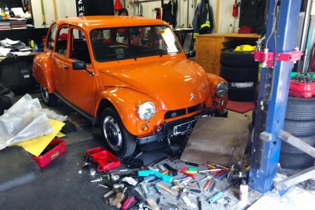 Voiture vintage orange sur pont élévateur avec outils éparpillés