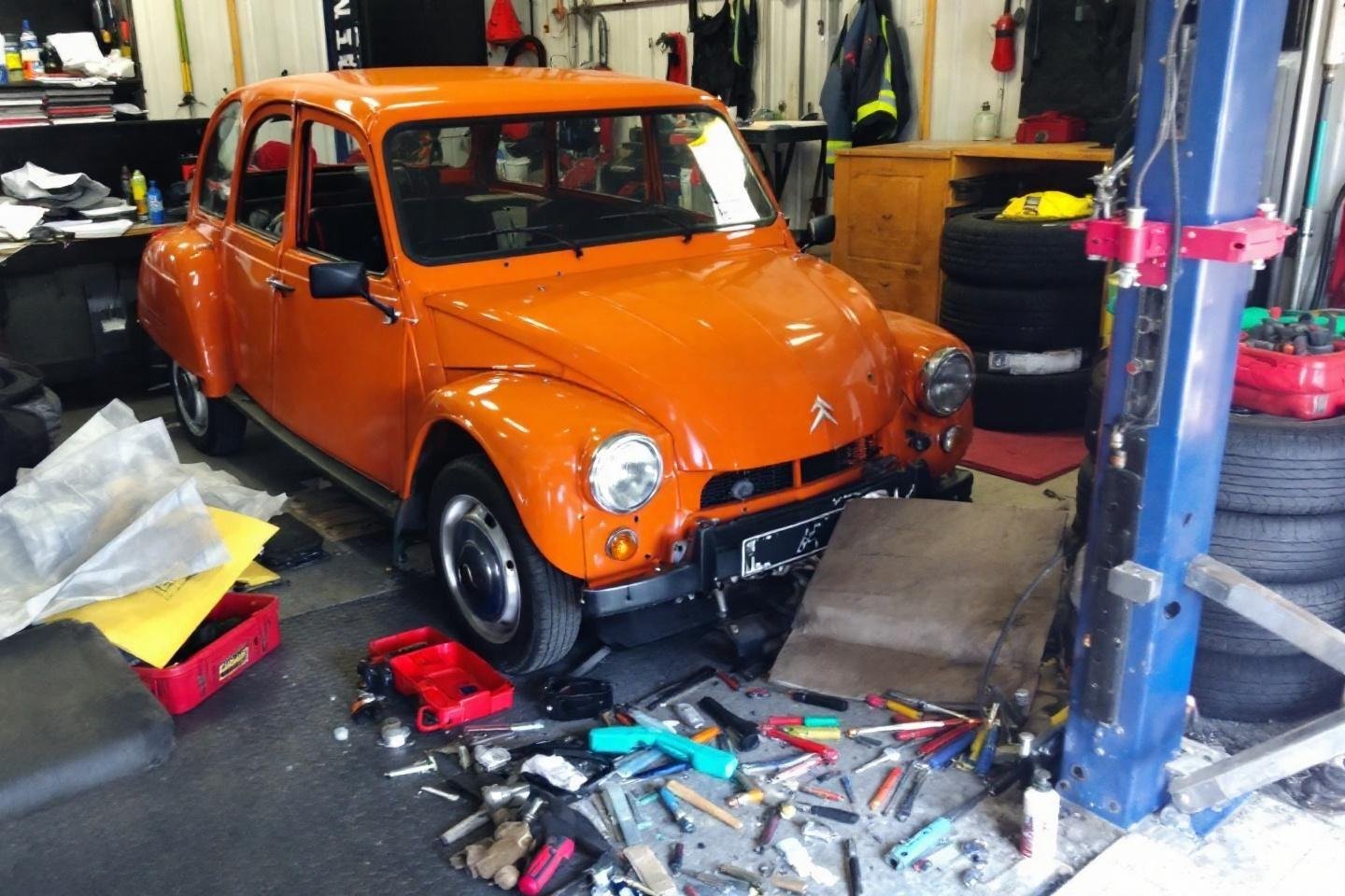 Voiture vintage orange sur pont élévateur avec outils éparpillés